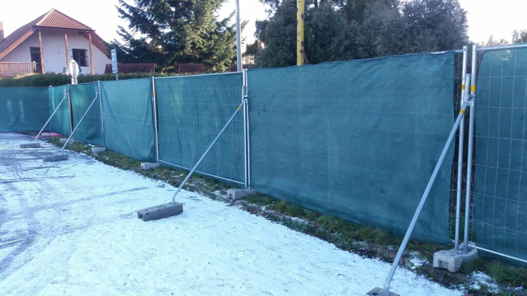 Mobilní oplocení se stínící tkaninou na betonových patkách v zimě